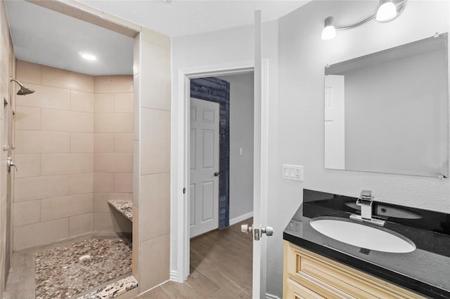 bathroom with vanity, wood-type flooring, and tiled shower