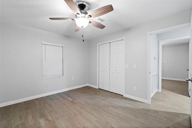 unfurnished bedroom featuring ceiling fan, a closet, and light wood-type flooring