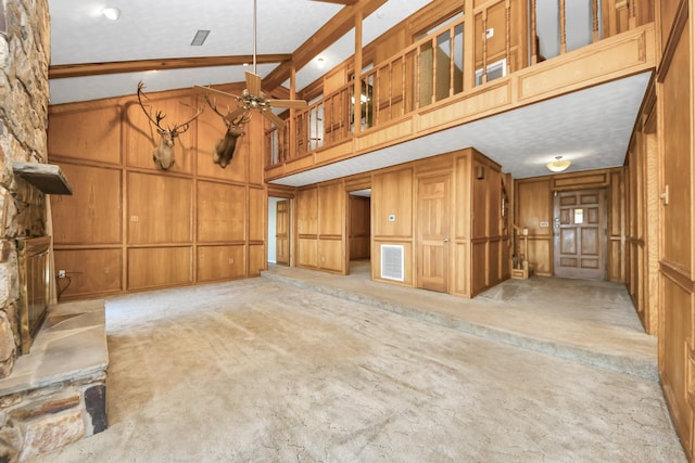 unfurnished living room with ceiling fan, high vaulted ceiling, light carpet, beamed ceiling, and wood walls