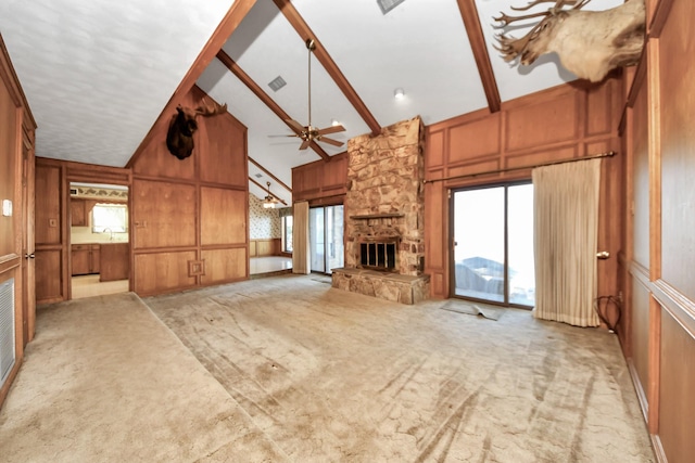 unfurnished living room with ceiling fan, beam ceiling, high vaulted ceiling, a wealth of natural light, and light colored carpet