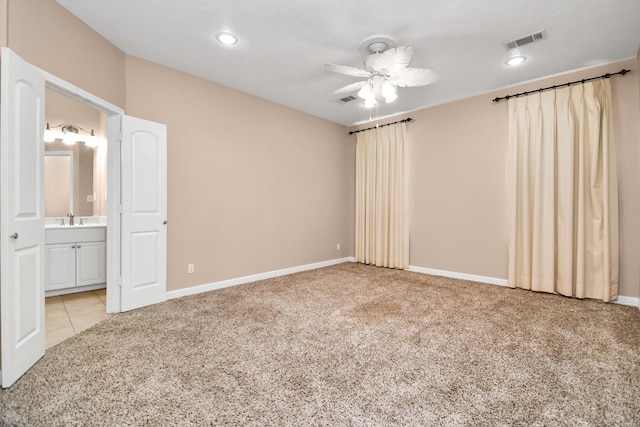 unfurnished bedroom featuring ceiling fan, connected bathroom, sink, and light carpet