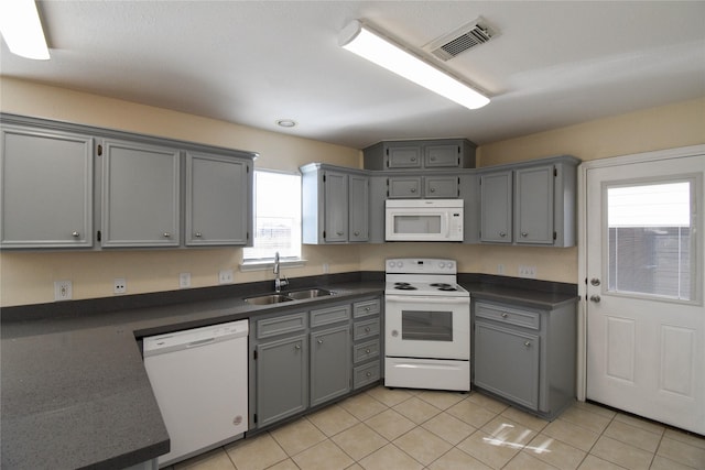 kitchen with light tile patterned flooring, white appliances, sink, and gray cabinetry