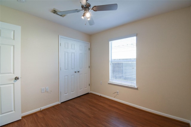 unfurnished bedroom with dark wood-type flooring, ceiling fan, and a closet