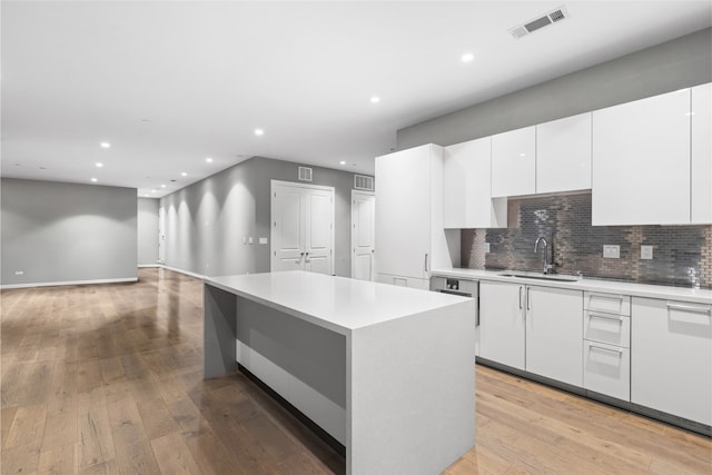 kitchen with sink, tasteful backsplash, a kitchen island, and white cabinetry