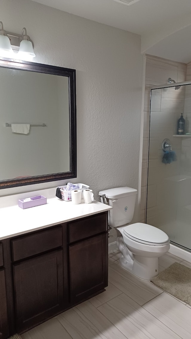 bathroom featuring vanity, an enclosed shower, and toilet