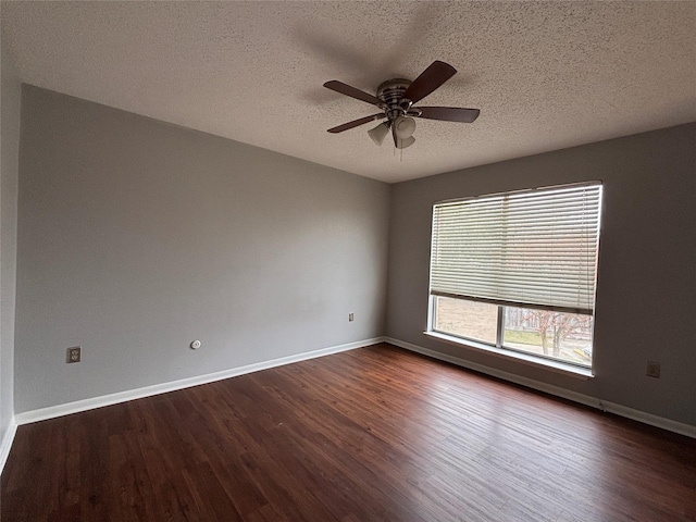 empty room featuring ceiling fan, dark wood-type flooring, and a textured ceiling