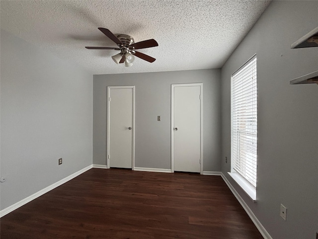 unfurnished bedroom featuring dark wood-type flooring, a textured ceiling, and ceiling fan