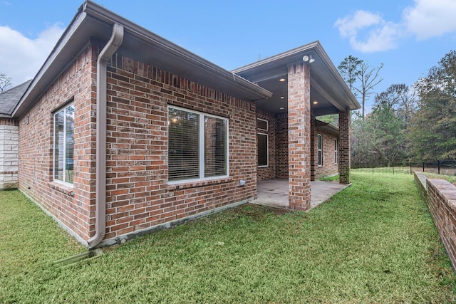 view of side of home featuring a patio area and a lawn