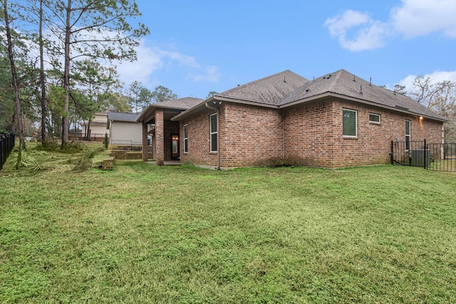 rear view of property with a yard and central air condition unit