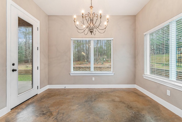 unfurnished dining area featuring an inviting chandelier, concrete floors, and a wealth of natural light