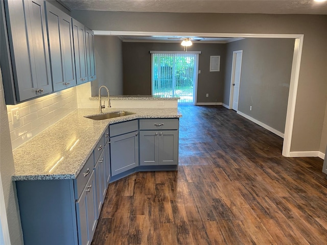 kitchen with sink, light stone counters, dark hardwood / wood-style flooring, and kitchen peninsula