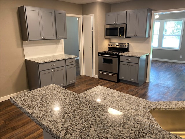 kitchen featuring appliances with stainless steel finishes, light stone countertops, and gray cabinetry