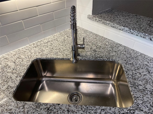 interior details with sink, backsplash, and light stone counters