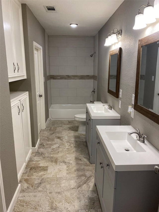 full bathroom featuring vanity, tiled shower / bath combo, and toilet