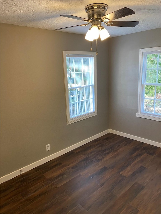 unfurnished room with dark wood-type flooring, a wealth of natural light, a textured ceiling, and ceiling fan