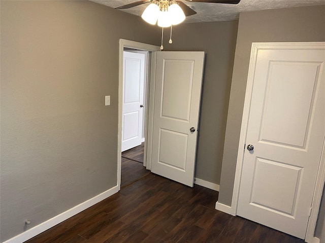 interior space featuring a textured ceiling, dark wood-type flooring, and ceiling fan