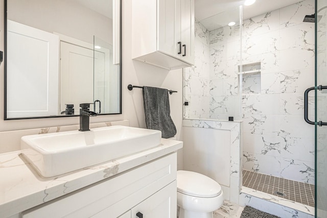 bathroom featuring a shower with door, vanity, and toilet