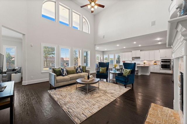 living room with dark hardwood / wood-style flooring, ceiling fan, and a high ceiling