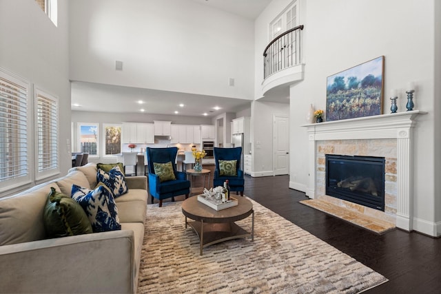 living room featuring a towering ceiling, dark hardwood / wood-style floors, and a tiled fireplace