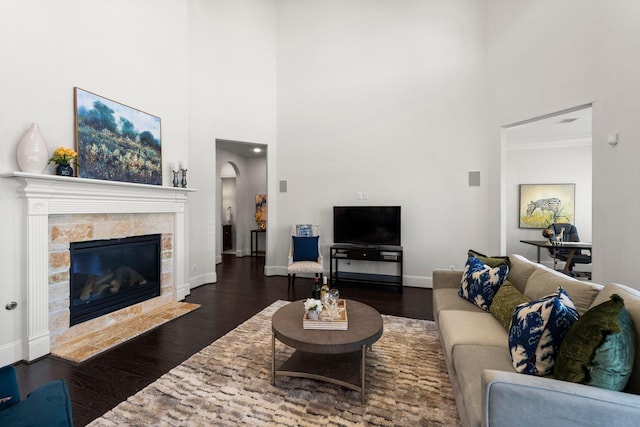 living room with ornamental molding, dark hardwood / wood-style floors, a fireplace, and a towering ceiling