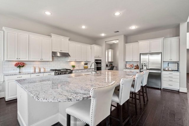 kitchen with white cabinetry, a spacious island, appliances with stainless steel finishes, and dark hardwood / wood-style flooring