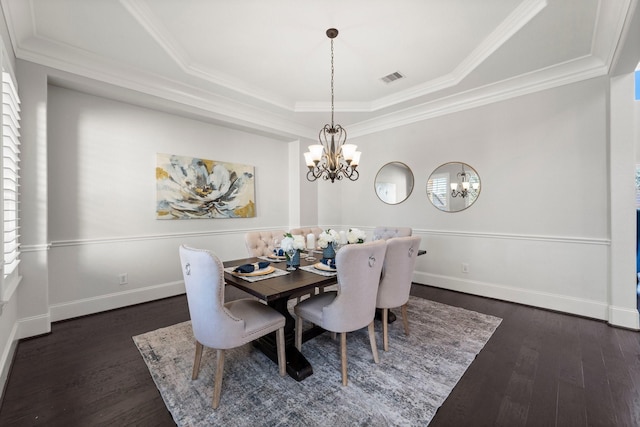 dining room with ornamental molding, dark hardwood / wood-style floors, a chandelier, and a tray ceiling