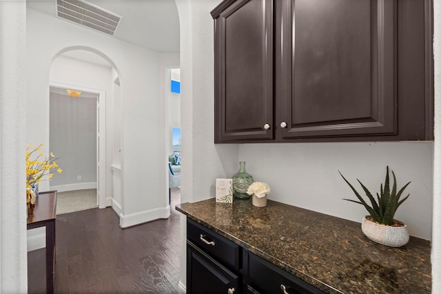 interior space with dark stone counters, dark hardwood / wood-style flooring, and dark brown cabinets