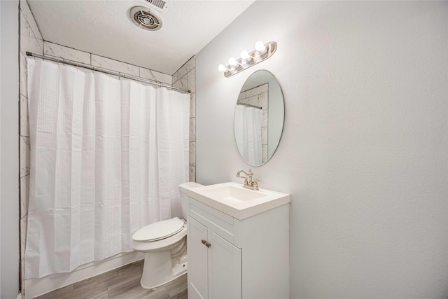 full bathroom with hardwood / wood-style flooring, vanity, toilet, shower / bathtub combination with curtain, and a textured ceiling