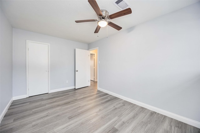 unfurnished bedroom featuring ceiling fan, light hardwood / wood-style floors, and a closet