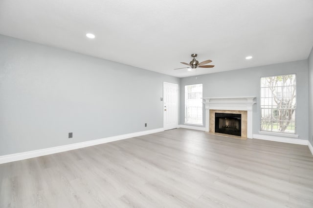 unfurnished living room featuring a fireplace, ceiling fan, and light wood-type flooring