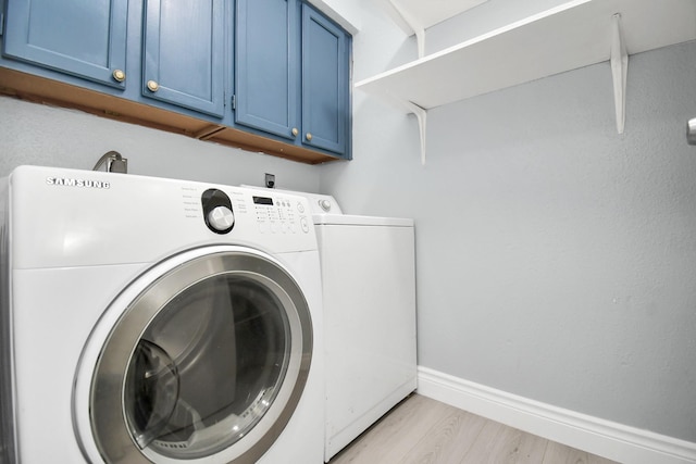 laundry room with cabinets, washing machine and dryer, and light wood-type flooring