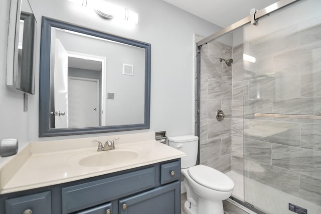 bathroom featuring vanity, toilet, and a shower with door