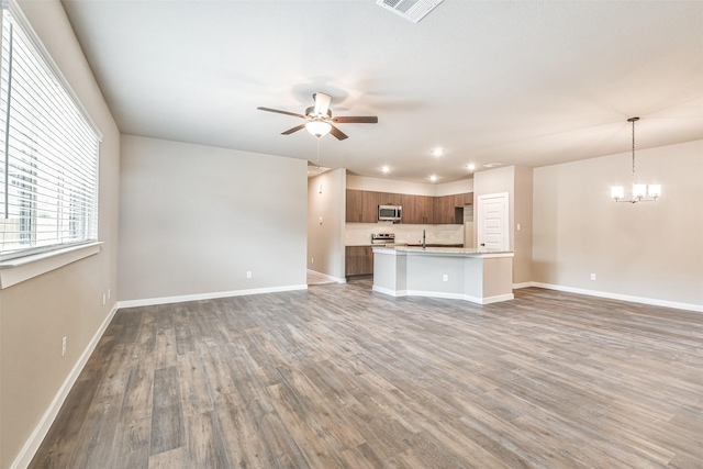 unfurnished living room with sink, dark hardwood / wood-style flooring, and ceiling fan with notable chandelier