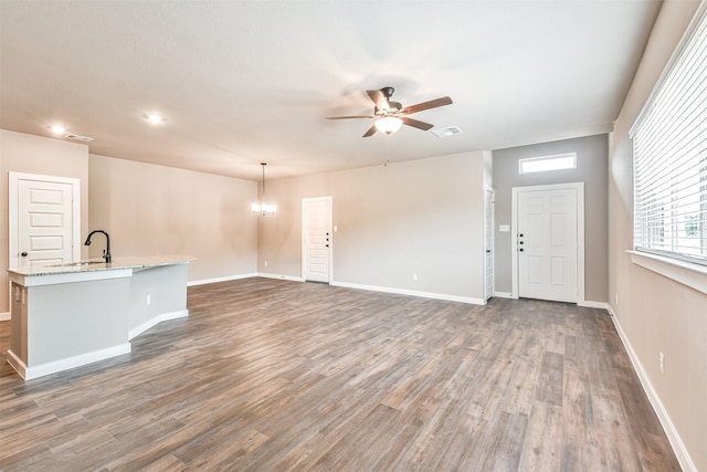 unfurnished living room featuring dark hardwood / wood-style floors and ceiling fan with notable chandelier