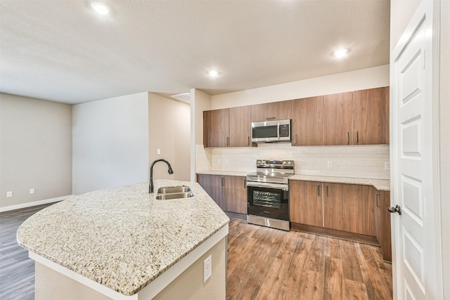 kitchen with dark hardwood / wood-style floors, tasteful backsplash, sink, a kitchen island with sink, and stainless steel appliances