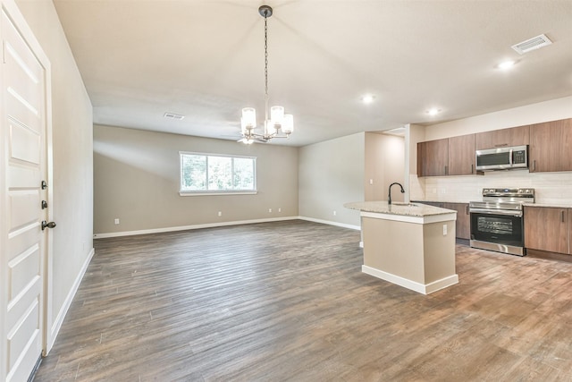 kitchen with sink, a kitchen island with sink, stainless steel appliances, dark hardwood / wood-style floors, and decorative light fixtures