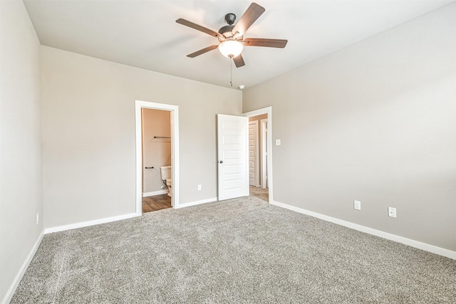 unfurnished bedroom with a walk in closet, a closet, ceiling fan, and carpet flooring