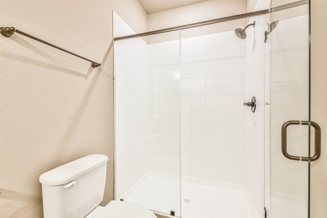 bathroom featuring a shower with shower door and toilet