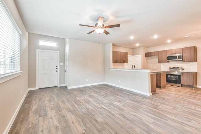 kitchen featuring ceiling fan, appliances with stainless steel finishes, kitchen peninsula, and light hardwood / wood-style flooring