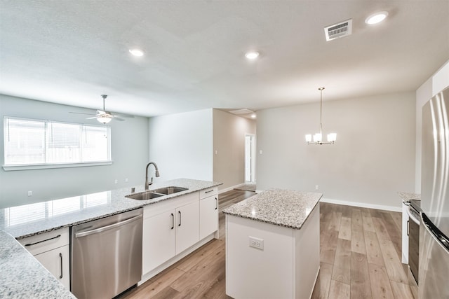 kitchen featuring a kitchen island, decorative light fixtures, sink, white cabinets, and stainless steel appliances