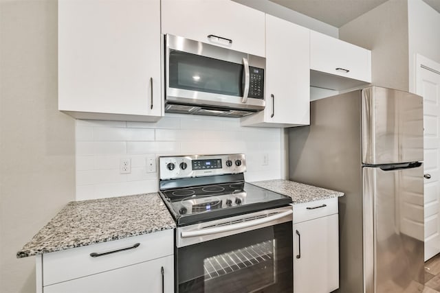 kitchen featuring white cabinetry, light stone countertops, decorative backsplash, and stainless steel appliances