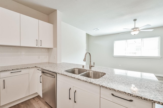 kitchen with white cabinetry, dishwasher, sink, light hardwood / wood-style floors, and kitchen peninsula