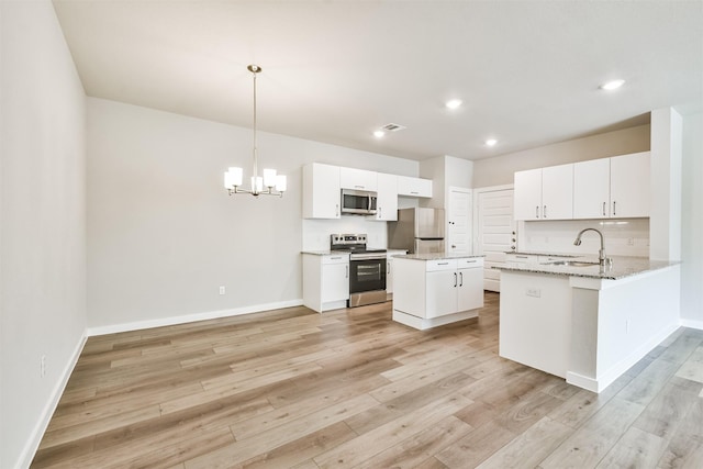 kitchen with pendant lighting, kitchen peninsula, white cabinets, and appliances with stainless steel finishes