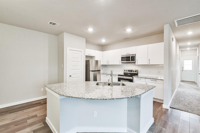 kitchen with an island with sink, appliances with stainless steel finishes, sink, and white cabinets