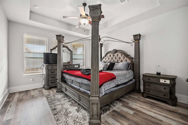 bedroom featuring dark hardwood / wood-style flooring, a raised ceiling, and ceiling fan