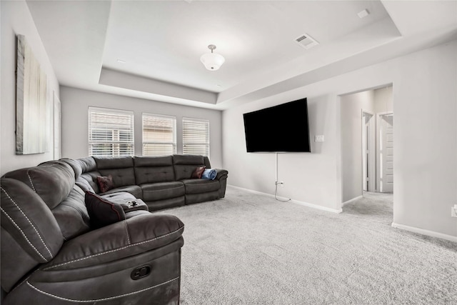 carpeted living room with a tray ceiling