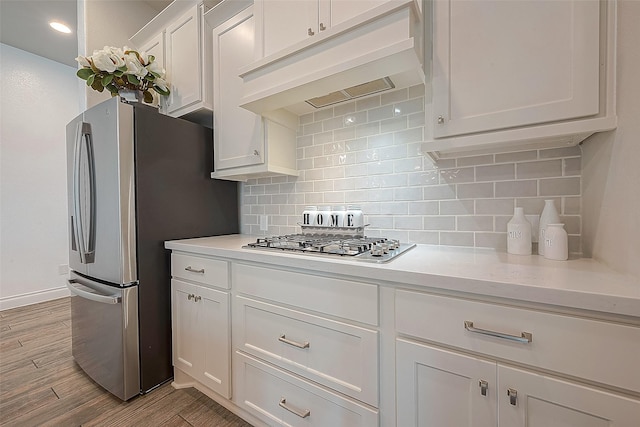 kitchen with white cabinetry, backsplash, custom range hood, and appliances with stainless steel finishes