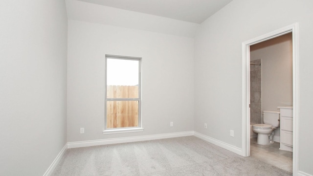 unfurnished bedroom featuring ensuite bath and light carpet