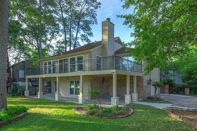 back of house featuring a wooden deck, a lawn, and a patio area