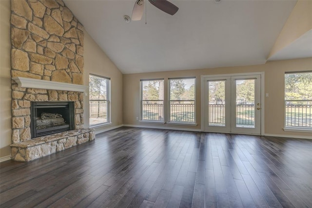 unfurnished living room featuring a stone fireplace, dark wood-type flooring, high vaulted ceiling, and ceiling fan